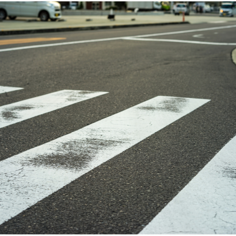 Zebrastreifen auf einer Straßenkreuzung mit Abnutzungsspuren.