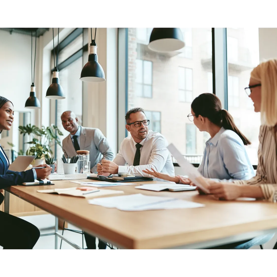Vier Personen sitzen an einem Tisch und diskutieren in einem modernen Büro.