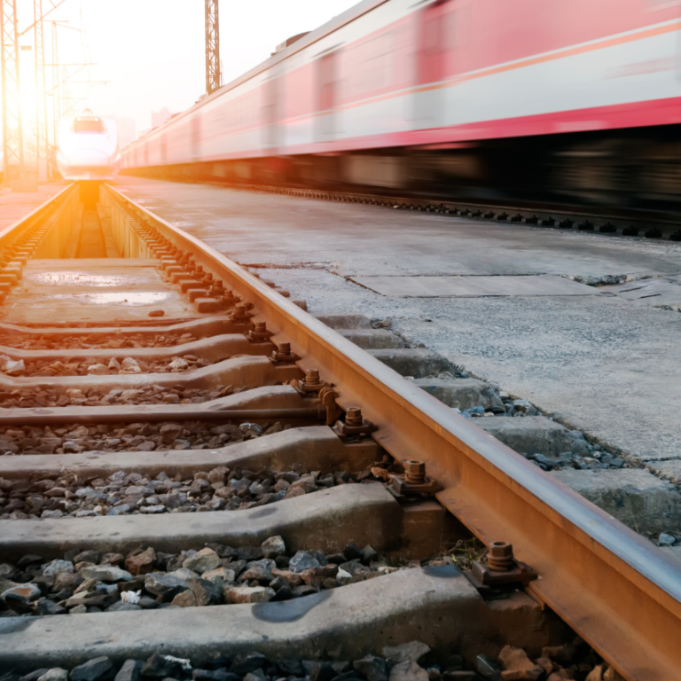 Schnell fahrender Zug auf Schienen bei Sonnenuntergang.