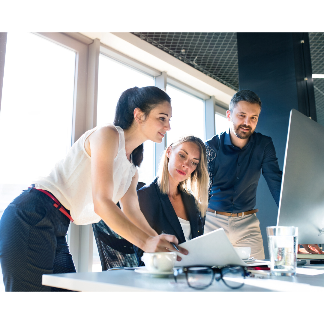 Drei Personen arbeiten gemeinsam an einem Computer in einem modernen Büro.