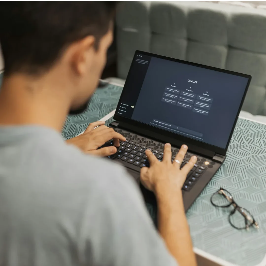 Ihre eigenen LLMs sicher und compliant managen Junger Mann arbeitet an einem Laptop, daneben liegen eine Brille und ein notizartiger Hintergrund.