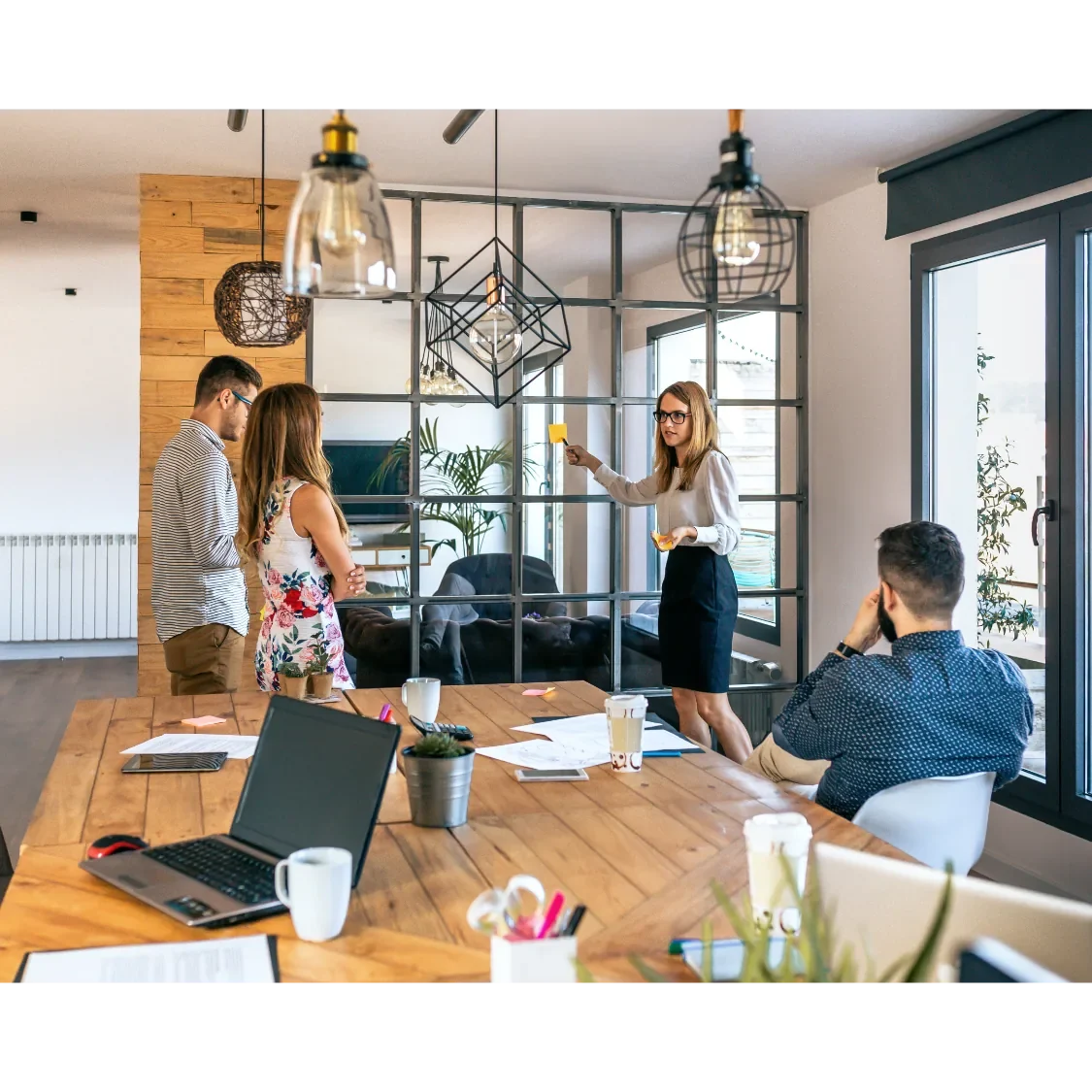 Besprechung in modernem Büro mit drei Personen, eine präsentiert mit Flipchart.